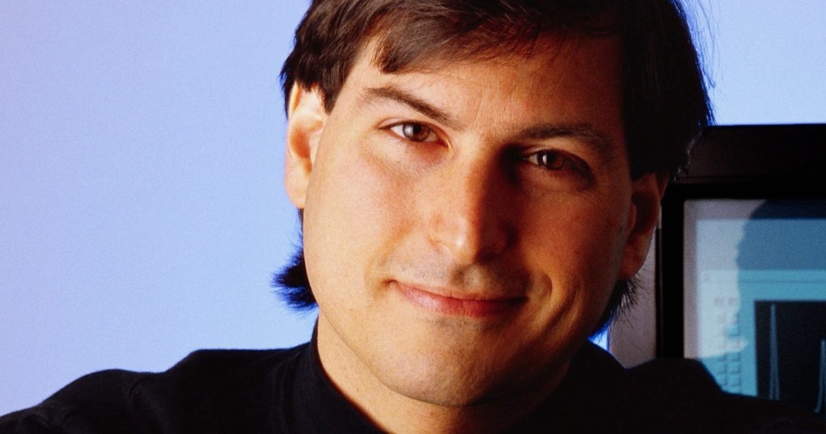 Tim Cook and Steve Jobs celebrating Apple's 50th anniversary with a commemorative laptop review.