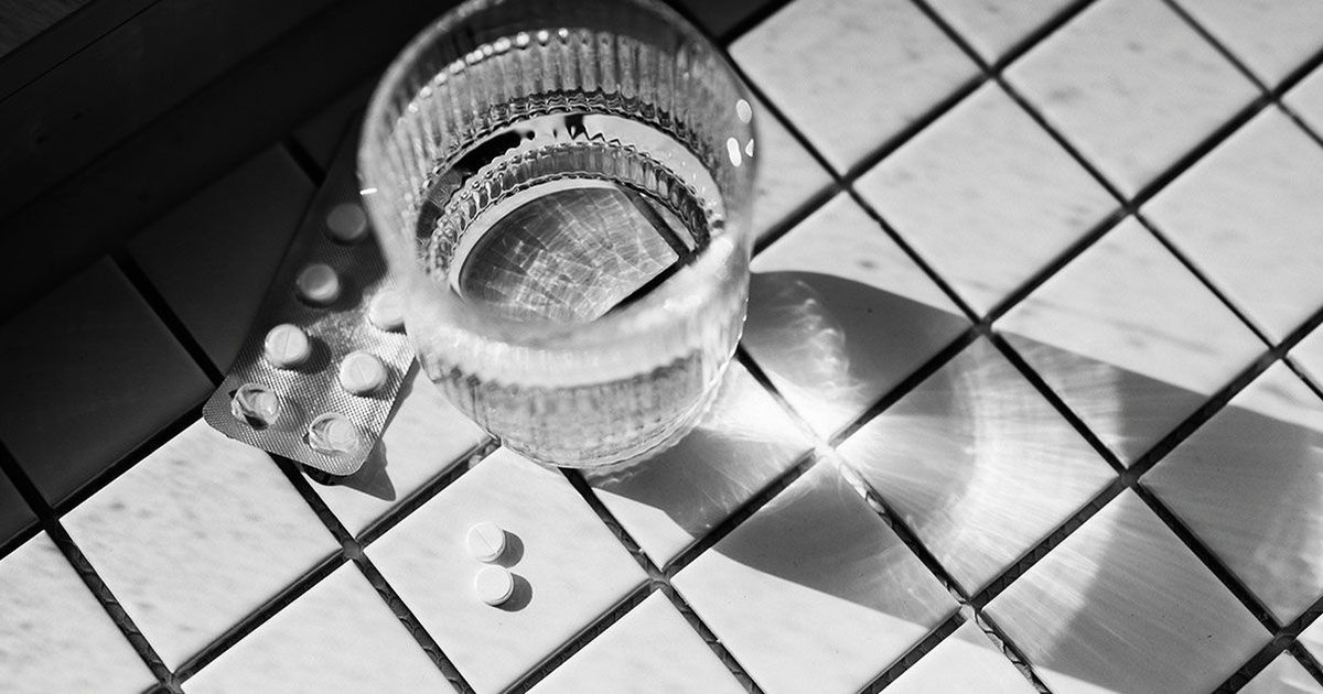 Aspirin tablet next to a glass of water, representing health and cancer prevention.