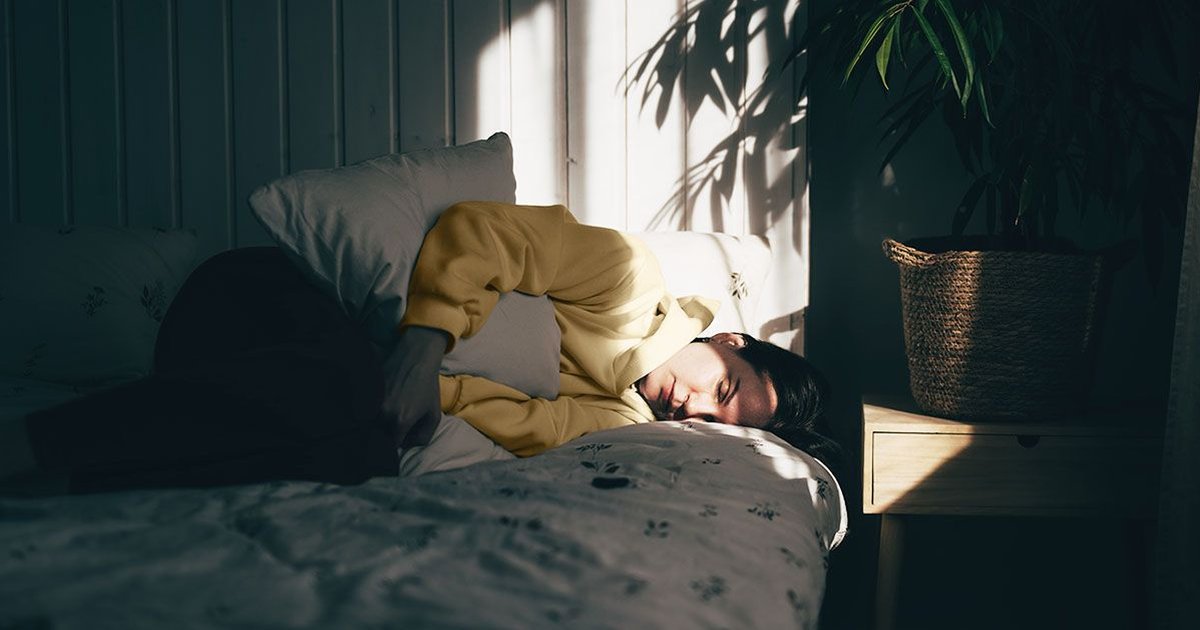 Person in bed holding stomach, highlighting the impact of Clostridioides Difficile infections.
