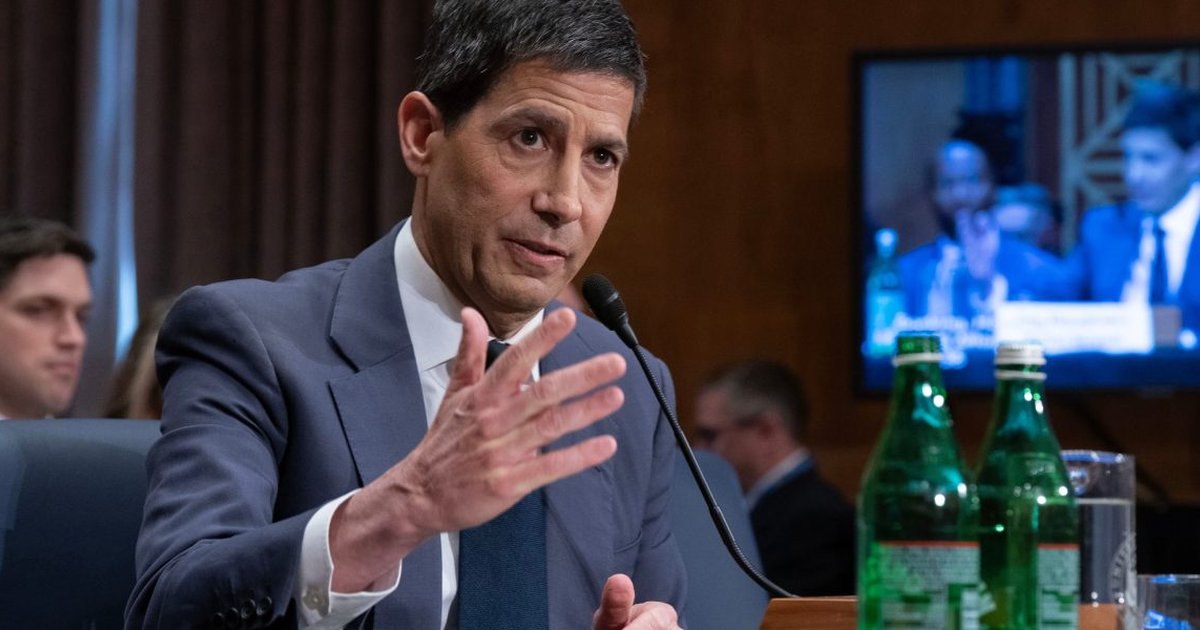 Kevin Warsh speaking at a financial conference, analyzing Fed policies and stock market impacts.