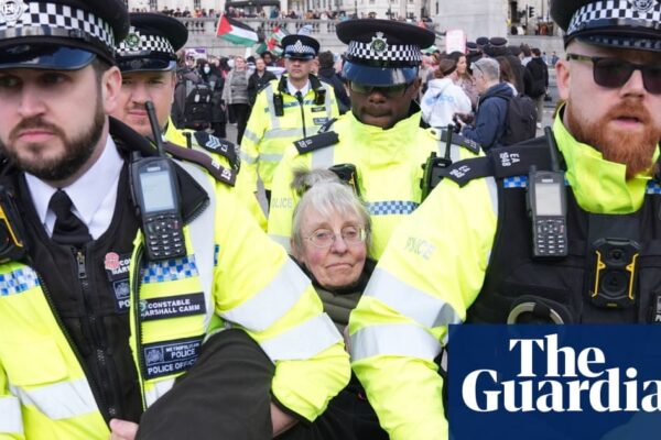 Demonstrators in Trafalgar Square holding signs supporting Palestine Action during the protest.