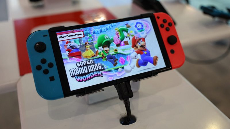 A Nintendo Switch handheld gaming console at a store with a demo of Super Mario Bros. Wonder displayed on the screen.