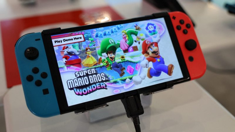 A Nintendo Switch handheld gaming console at a store with a demo of Super Mario Bros. Wonder displayed on the screen.